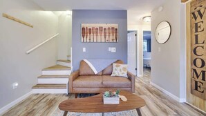A modern living room with a sofa, coffee table, and a painting on the wall.