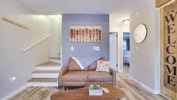Un salon moderne avec un canapé, une table basse et un tableau accroché au mur.