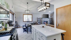 A modern kitchen with a central island, a dining area with a view, and a fireplace.
