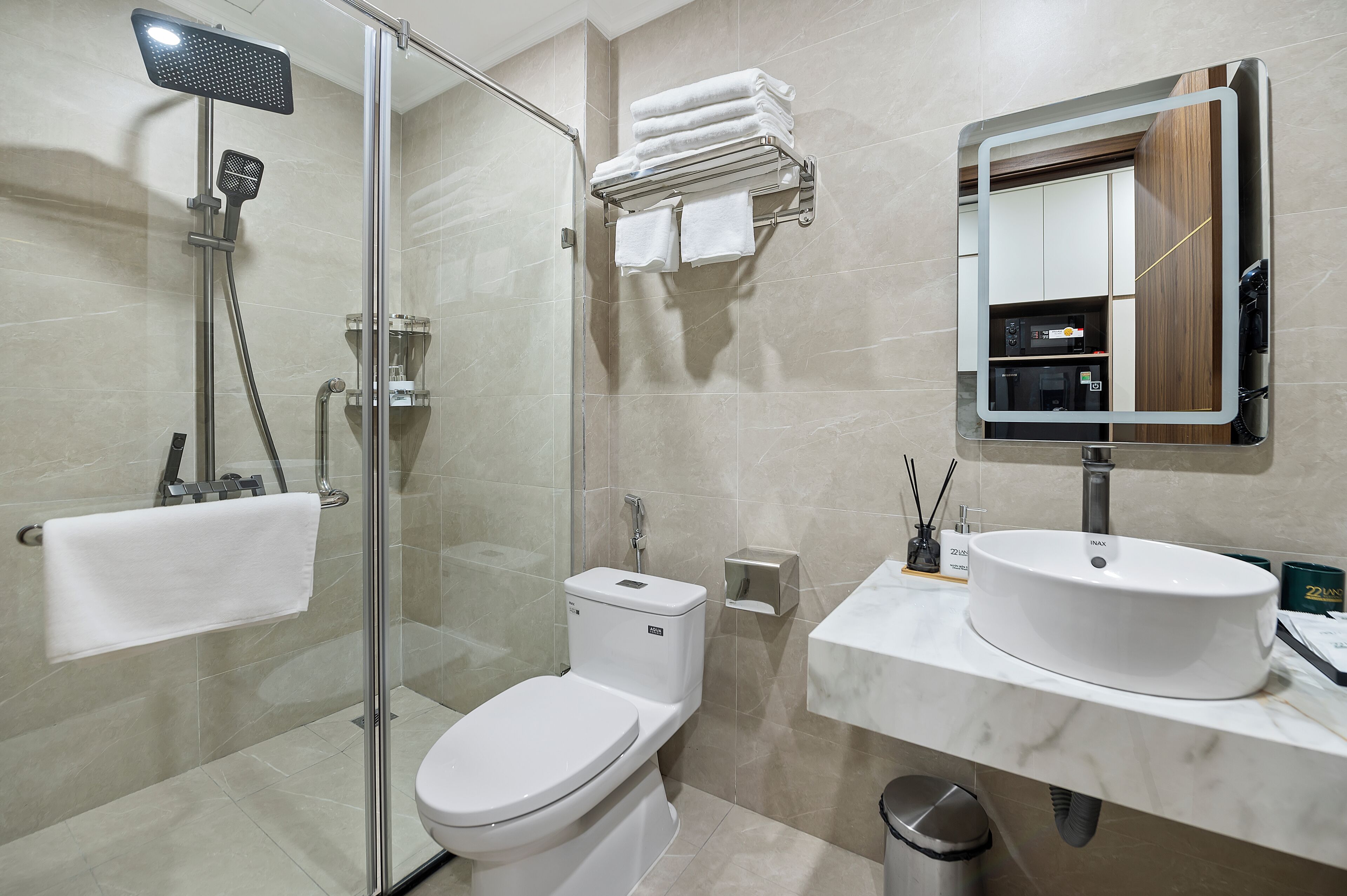 Een moderne badkamer met een douchecabine, toilet, wastafel met spiegel en een handdoekrek.