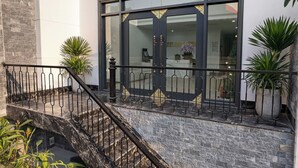 A hotel entrance with a stone staircase, metal railing, and potted plants. - Cosmos Hotel Apartment (Hanoi)