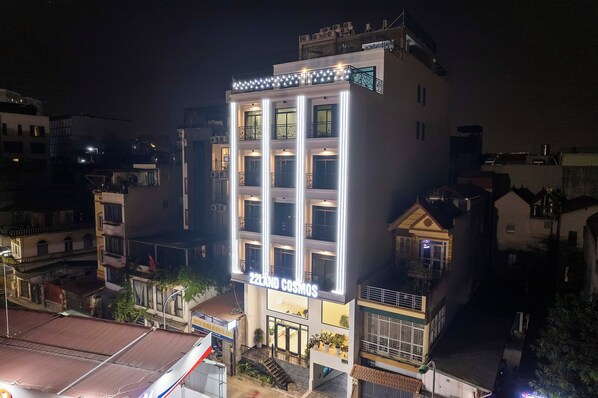 Um hotel com vários andares chamado "ZELAND COSMOS", com fachada moderna, varandas e sinalização iluminada.