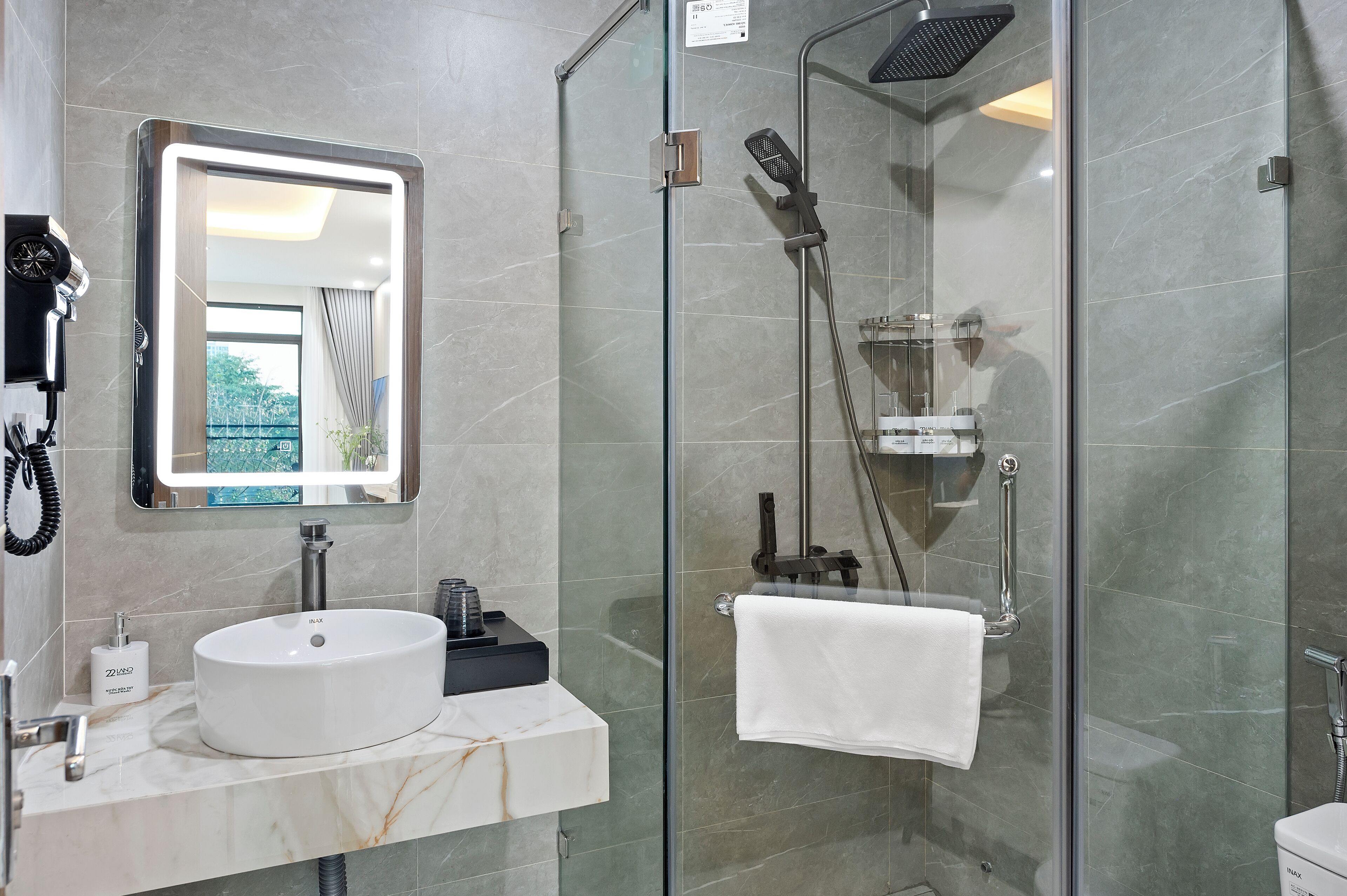 A modern bathroom with a glass-enclosed shower, a white sink, and a large mirror.