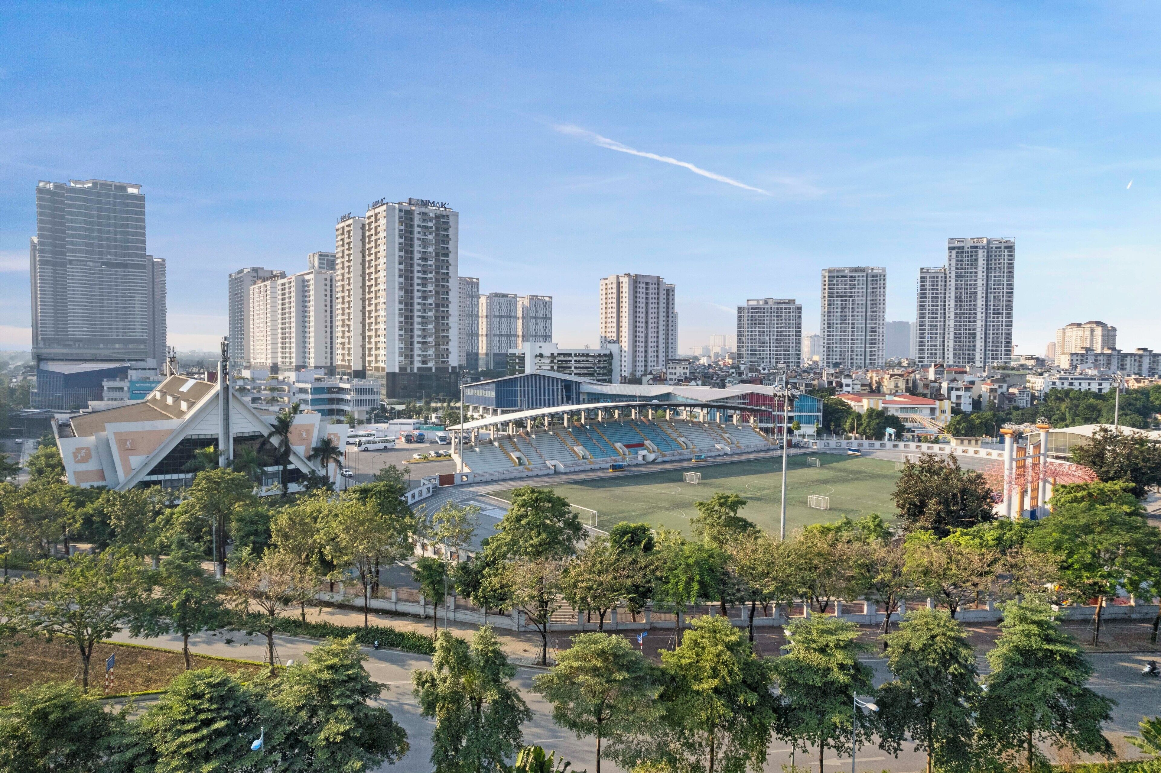 A cityscape with modern high-rise buildings, a stadium, and surrounding greenery.