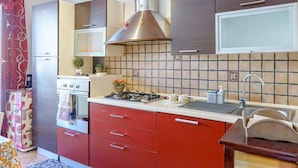 A kitchen with wooden beams, a gas stove, a stainless steel range hood, and a tiled backsplash. - At Mary's House II (Catania)