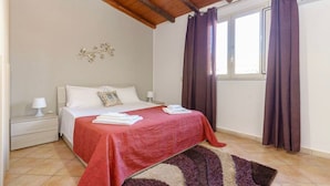 A bedroom with a bed, nightstands, a window with curtains, and a ceiling fan. - At Mary's House II (Catania)