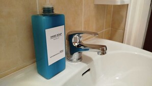 A bathroom sink with a blue hand soap dispenser and a chrome faucet. - Historic apartment on Avenue (Trieste)