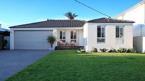 A single-story house with a garage, a front porch with two chairs, and a well-maintained lawn.