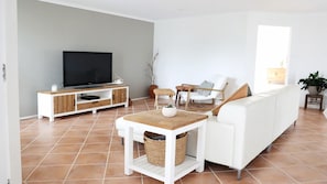 Una sala de estar moderna con televisor, sofá blanco y una mesita.
