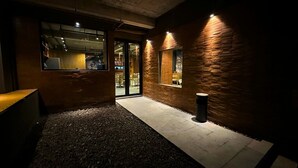 An interior space with a concrete ceiling, a brick wall, and a glass door leading to an outdoor area. - ALTHIA PRIVATE CAPSULE QUARTERS (Legian)