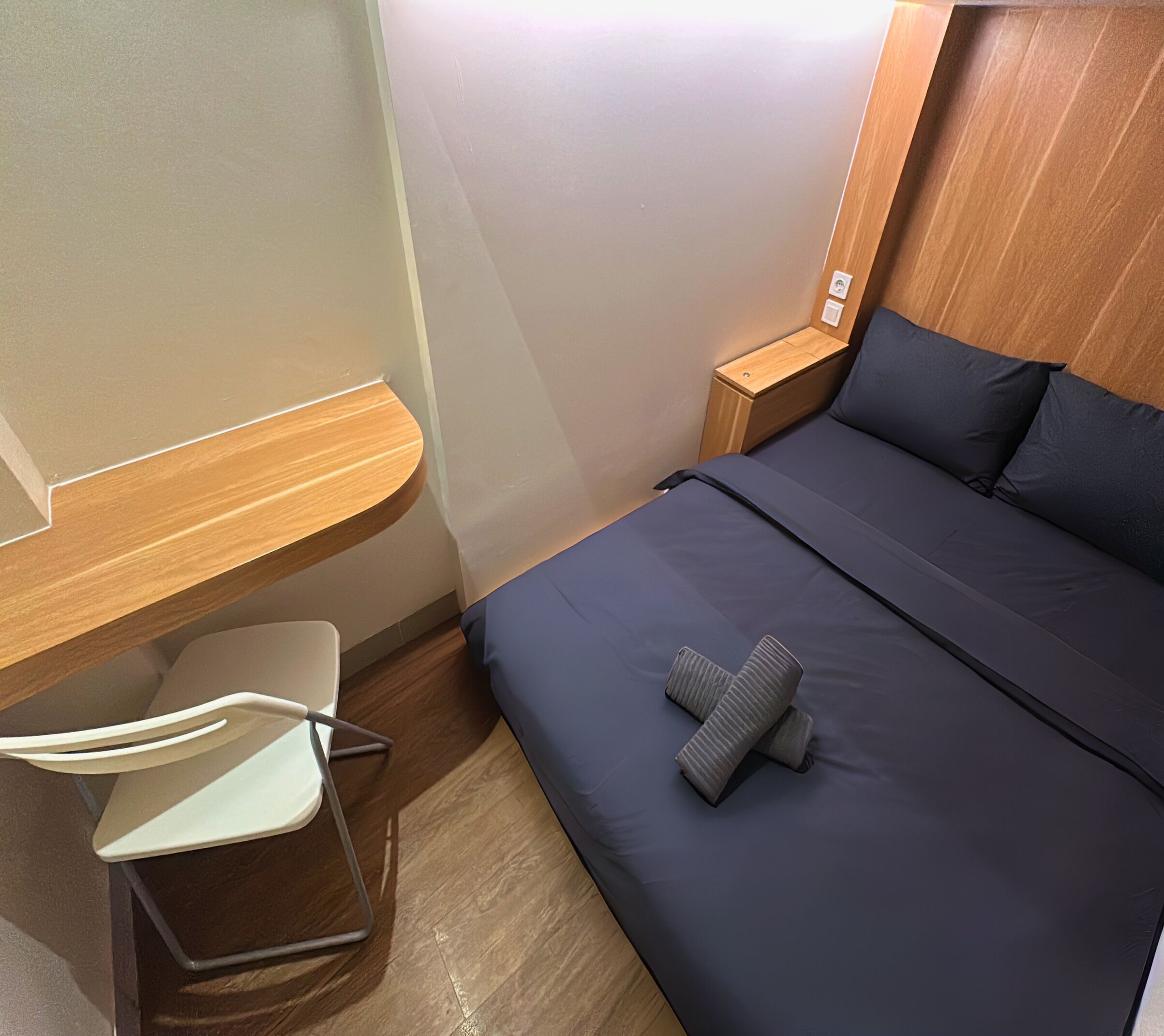 A compact hotel room with a bed, a small desk, and a chair.
