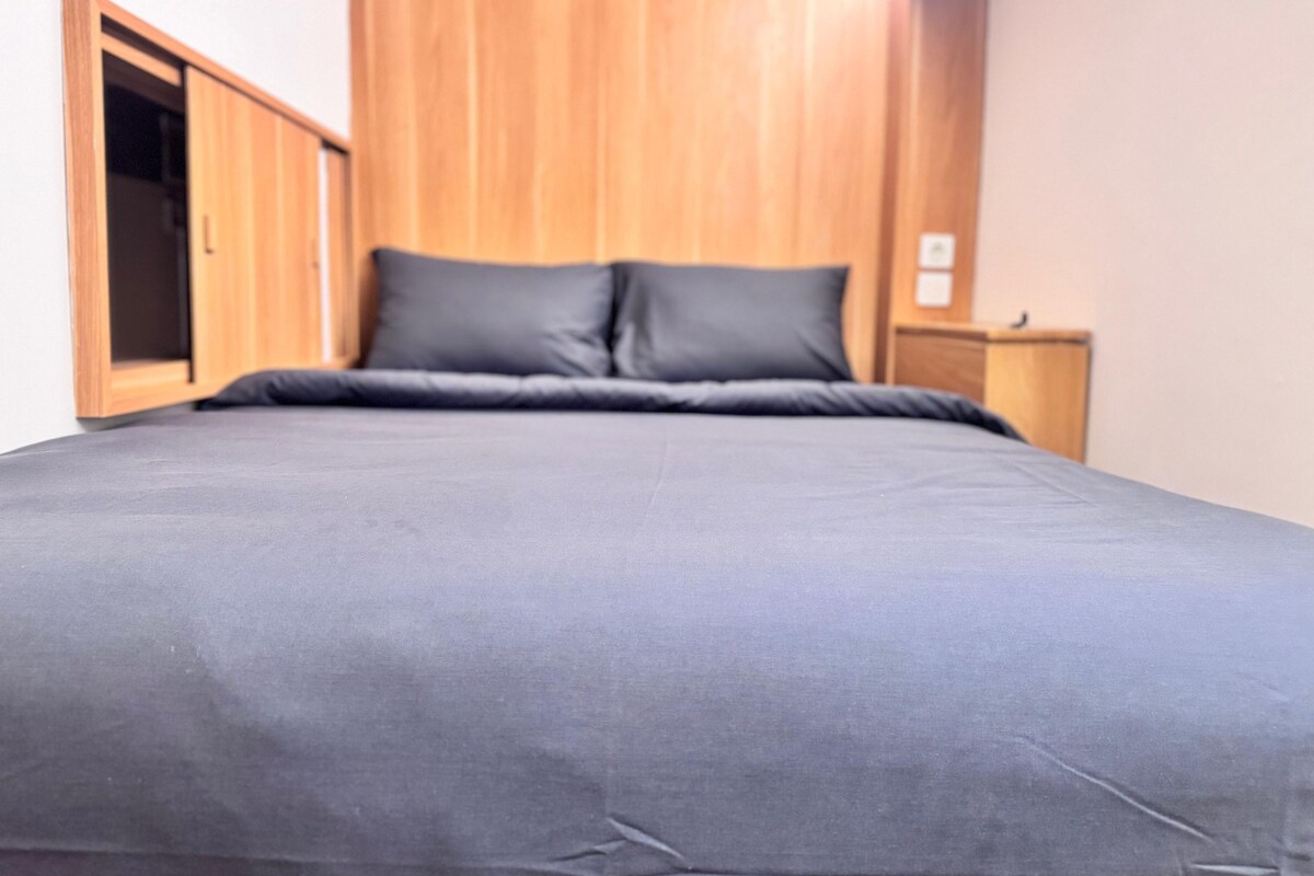 A bedroom with a bed, wooden wardrobe, and a nightstand.