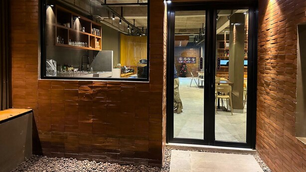 An interior with a brick wall, a window, and a door leading to an outdoor area. - ALTHIA PRIVATE CAPSULE QUARTERS (Legian)