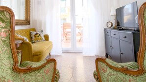 A room with a yellow armchair, a grey dresser with a TV, and a large mirror.