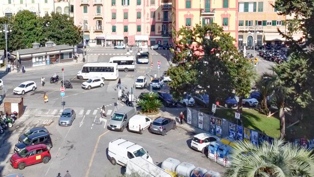 A busy urban street with buildings, parked cars, and a bus.
