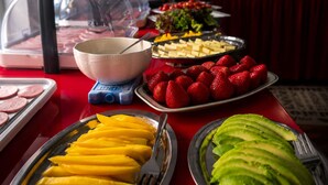 Une table de buffet proposant divers aliments, notamment des tranches de mangue, des fraises et des avocats.
