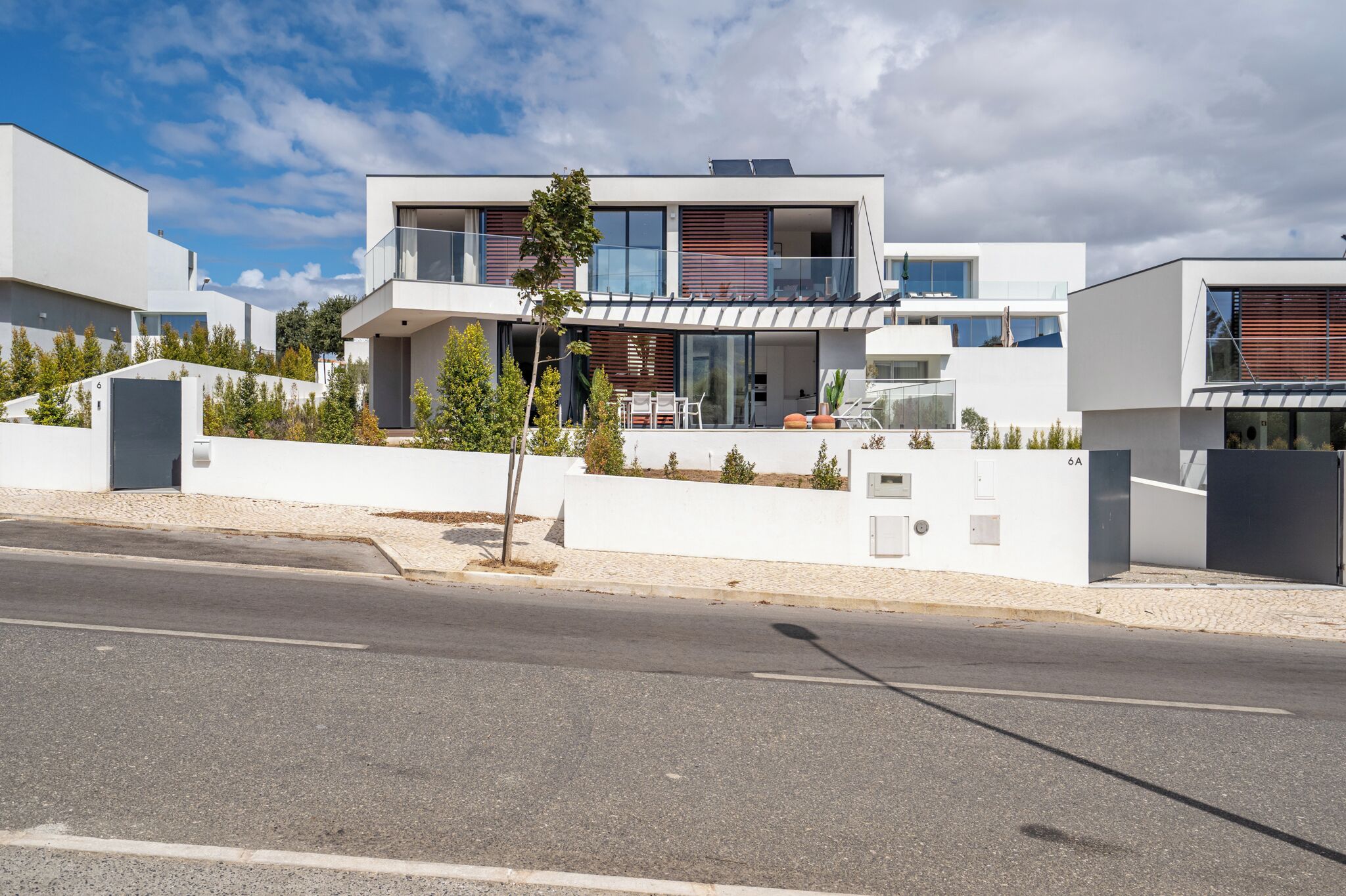 Una casa moderna de dos pisos con balcón, entrada para coches y un pequeño jardín.
