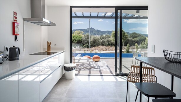 A modern kitchen with a view of a pool and mountains.