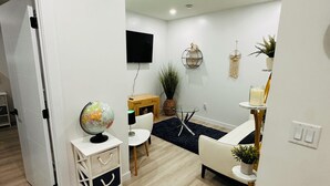 A modern living room with a flat-screen TV, a globe, a small table, a sofa, and a plant. - Cozy, 2BR apt., fully furnished! (Edmonton)