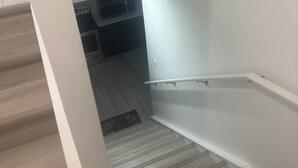 A staircase with wooden flooring leading to a kitchen area with a microwave and stove. - Cozy, 2BR apt., fully furnished! (Edmonton)