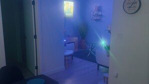 A modern living room with a flat-screen TV mounted on the wall, a clock, and a potted plant. - Cozy, 2BR apt., fully furnished! (Edmonton)