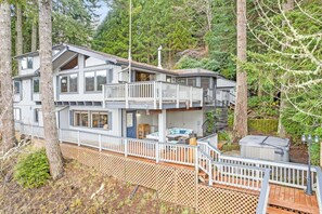 A multi-story cabin with a balcony, deck, and a small outdoor seating area. - Stay In Lakeside - Lake Front Oasis (Lakeside)