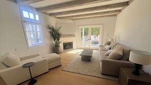 Un salon spacieux doté d’une cheminée, d’une grande fenêtre et d’un balcon.