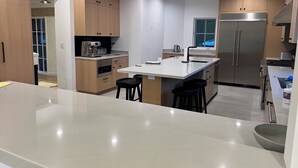 Une cuisine moderne dotée d’un îlot central, d’appareils électroménagers en acier inoxydable et de meubles de rangement en bois.