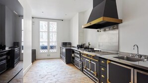 A modern kitchen with black cabinets, stainless steel appliances, and a large window.