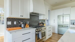 Una cocina moderna con armarios blancos, estufa a gas, horno y refrigerador.
