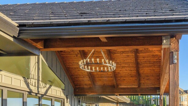 Una terraza al aire libre con una mesa y sillas de madera, una lámpara colgante y un sillón informal grande.