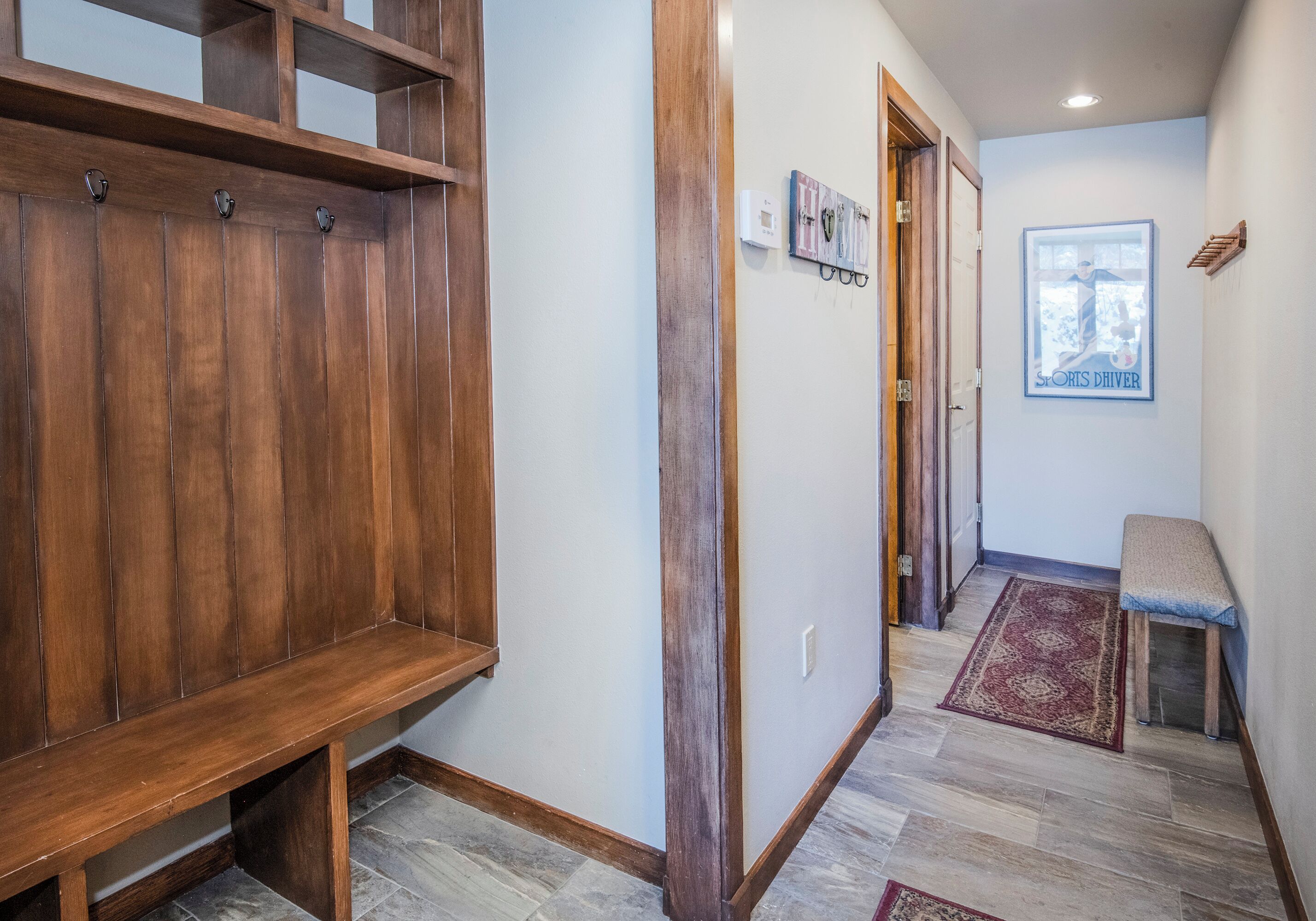 A hallway with a wooden bench, a rug, and a framed picture on the wall.