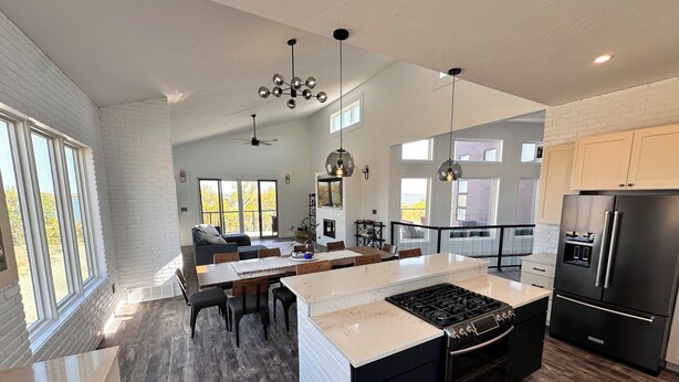 Una cocina moderna con una isla central, electrodomésticos negros y una zona de comedor con vistas.