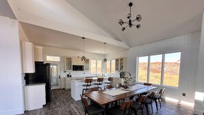 Una cocina amplia con paredes de ladrillo blanco, una isla grande y un comedor con mesa y sillas de madera.