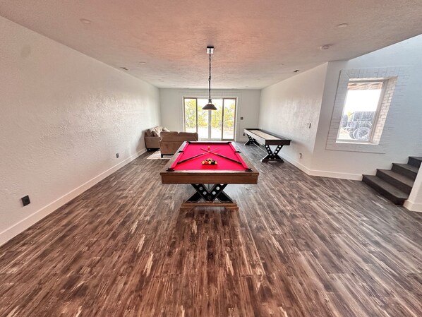 A spacious room with a pool table, a sofa, and a billiards table. - Spacious 5-Bedroom House on Lake McConaughey – Lake front, WiFi, AC (Brule)