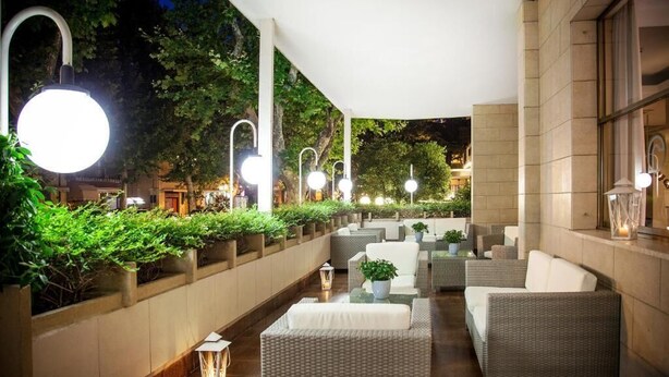 An outdoor seating area with wicker furniture, potted plants, and ambient lighting. - Hotel Rosabianca (Rimini)