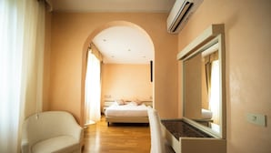 A hotel room with a bed, a chair, a built-in TV, and a large mirror. - Hotel Rosabianca (Rimini)
