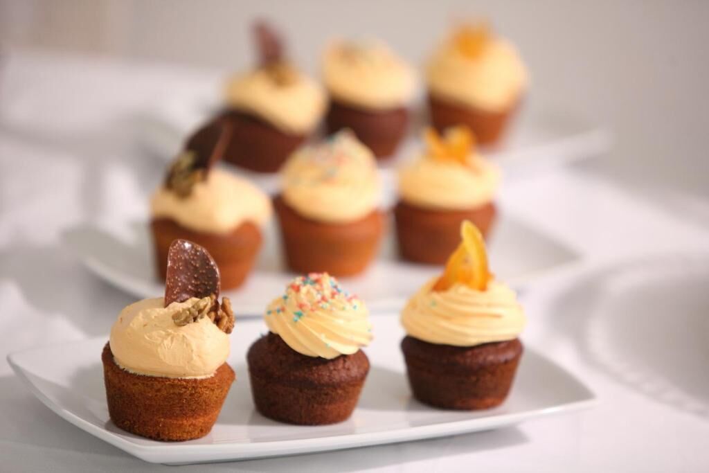 Ein weißer Teller mit drei Cupcakes, jeder mit einer anderen Glasur und Dekoration versehen.