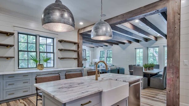 Una cocina moderna con una isla grande, iluminación colgante y vigas de madera a la vista.
