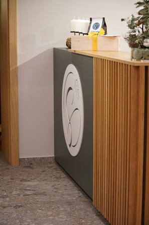 A reception desk with a modern design, featuring a logo, a small plant, and a candle. - Stieglers - Restaurant Hotel Biergarten (Ergoldsbach)