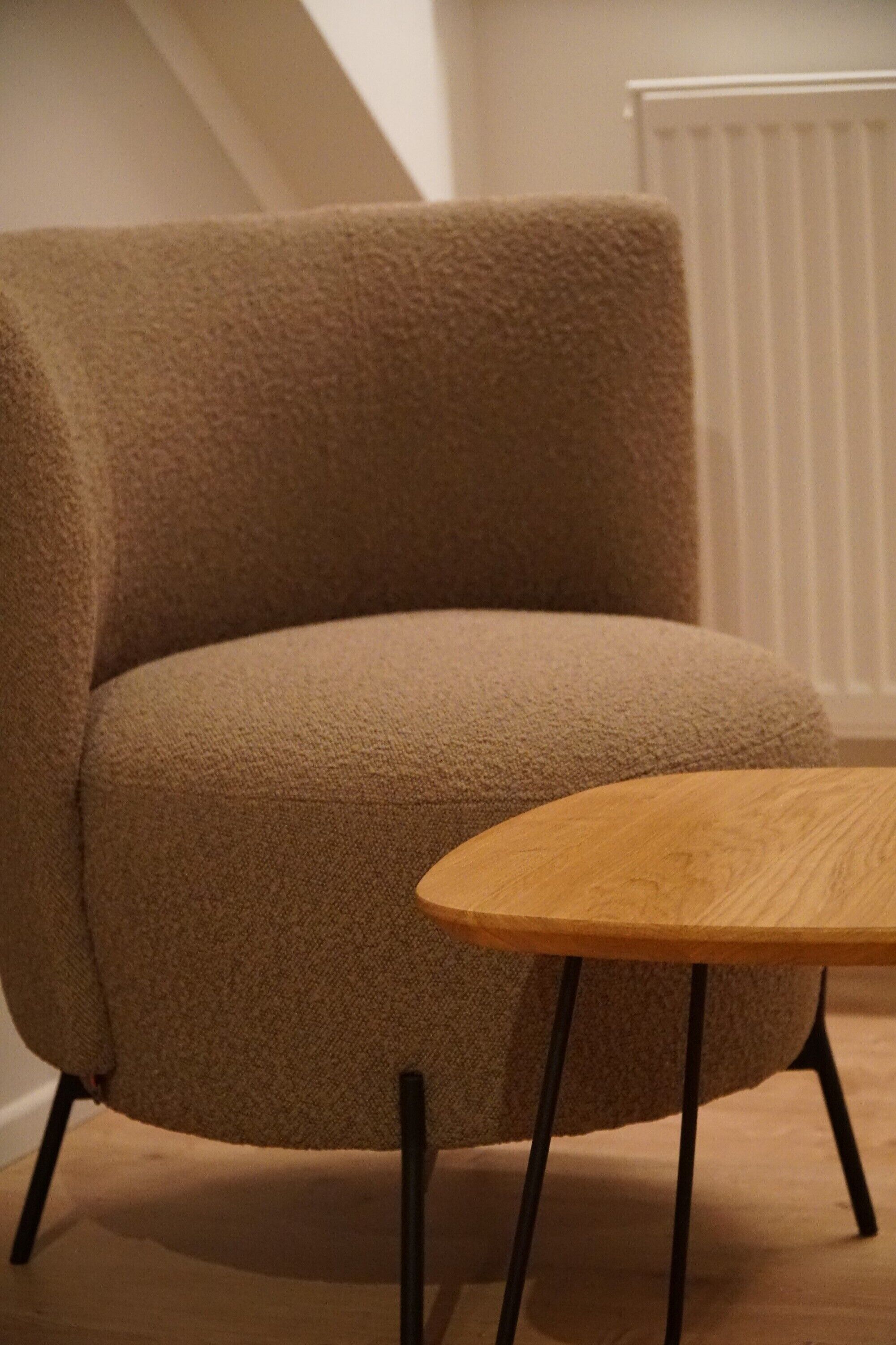 A beige armchair with a wooden table in front.