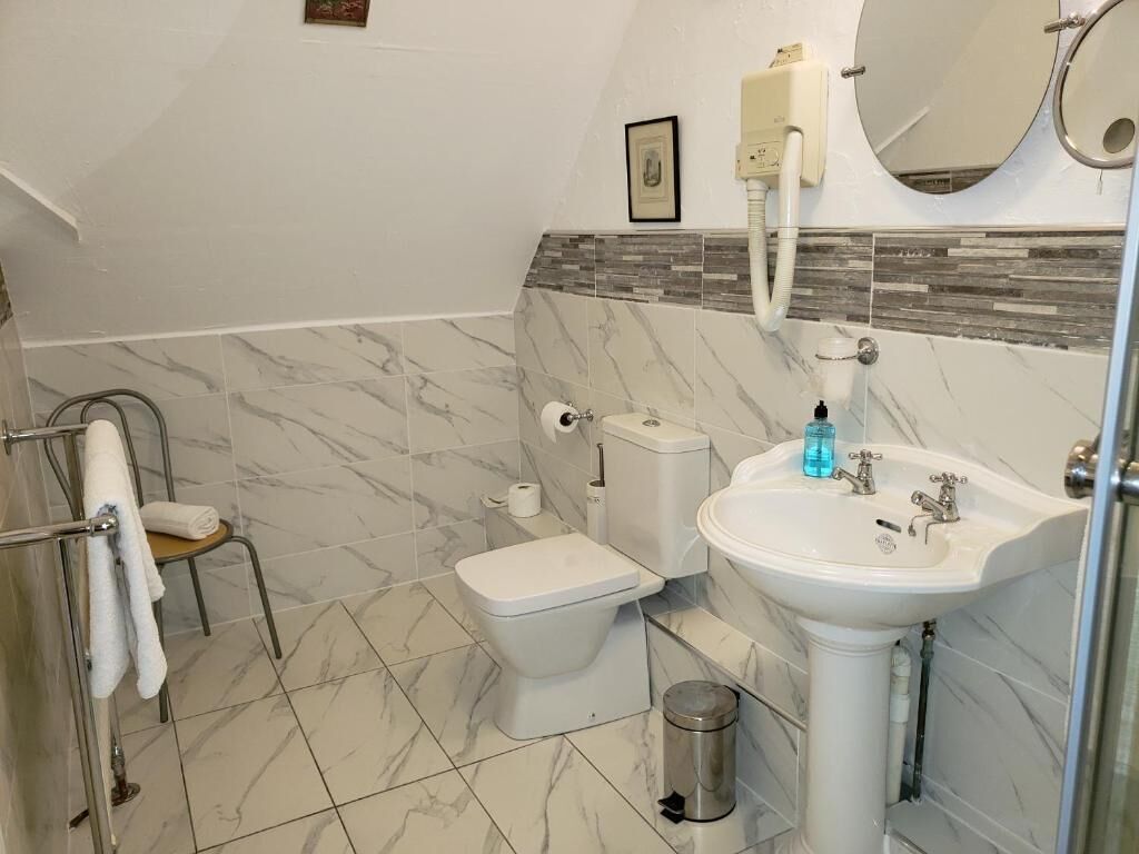 Een badkamer met toilet, wastafel en douchehoek.