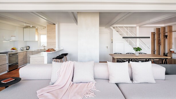 Un salon moderne avec un canapé, une table basse et un escalier menant à un niveau supérieur.