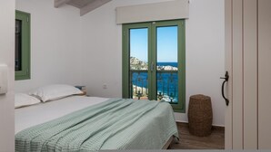 A bedroom with a bed, a window with a view of the sea, and a small round wicker basket. - Evilia Beach Villa With Private Pool (Zakynthos)