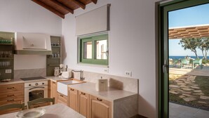 A modern kitchen with wooden cabinets, a built-in oven, and a large window with green shutters. - Evilia Beach Villa With Private Pool (Zakynthos)