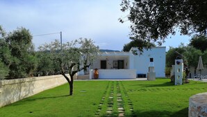 A modern building with a white exterior, a paved pathway leading to the entrance, and a stone wall on the left. - Villa Adriatica Near Ostuni Puglia (Ostuni)