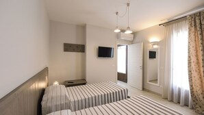 A hotel room with two beds, a TV, an air conditioner, a bedside table, and a mirror. - Villa Adriatica Near Ostuni Puglia (Ostuni)