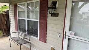 Une maison avec un porche, un banc, une boîte aux lettres et un panneau indiquant « Pas de démarcheurs ».