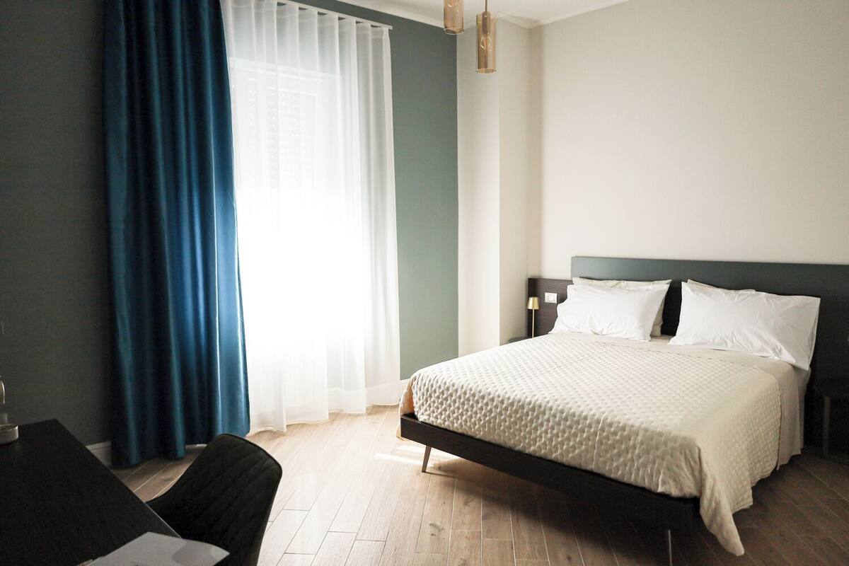 A hotel room with a bed, a desk, and a chair.