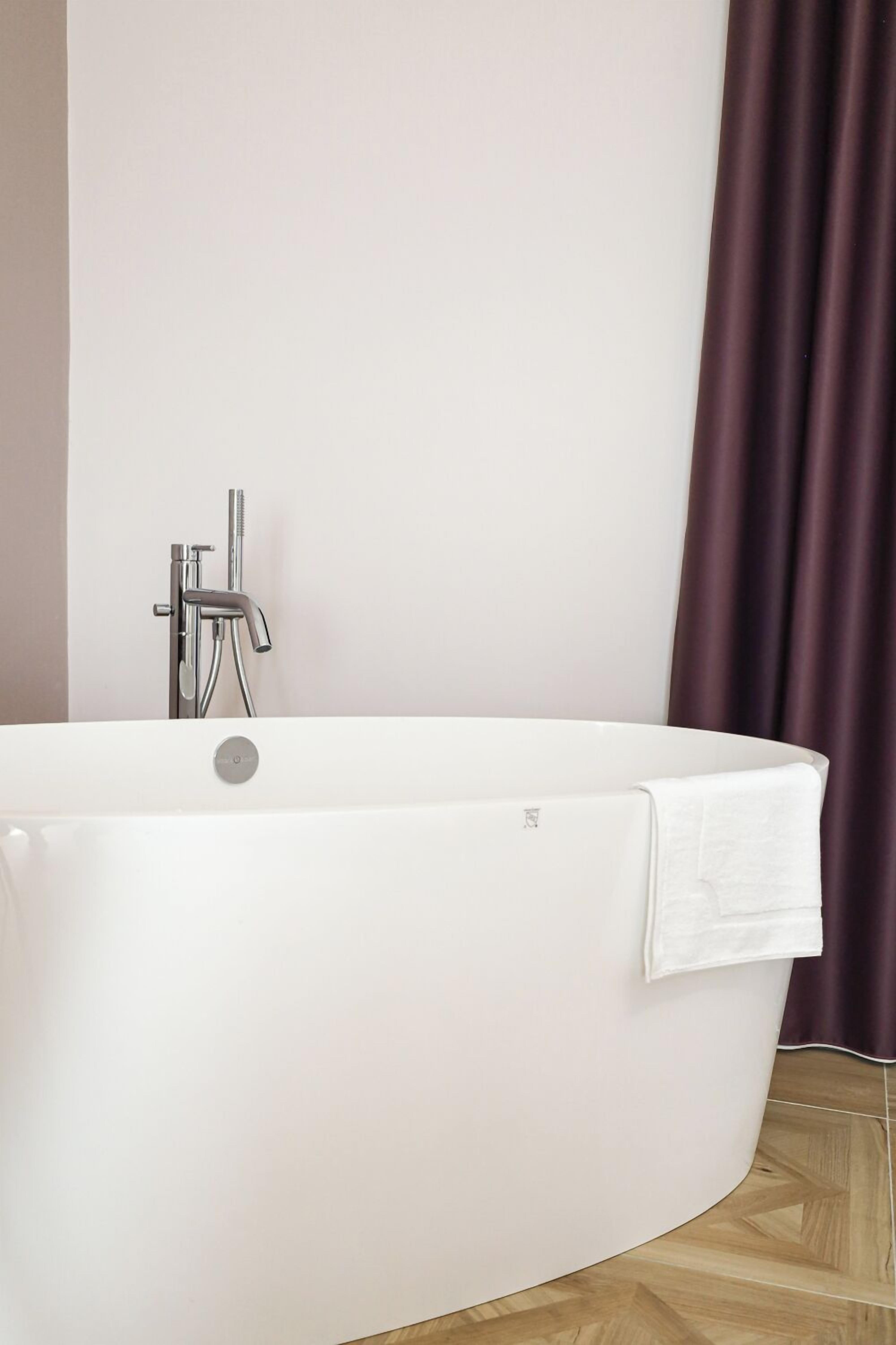 Un baño moderno con una bañera independiente, un cabezal de ducha manual y una toalla colgada a un lado.